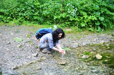 Bir serin orman Creek'ten saf su içme kadın seyahat