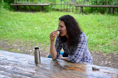 Kadın seyahat Termos şişe kapağı açık havada içki içer. Kız zammı sonra aittir.