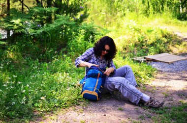 Kadın turist ile orman toprağa oturup sırt çantası