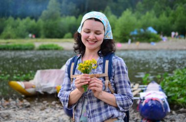 Seyahat kız nehir arka plan üzerinde doğadan alınan sarı çiçekler kokuyor