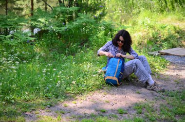 Kadın turist ile orman toprağa oturup sırt çantası