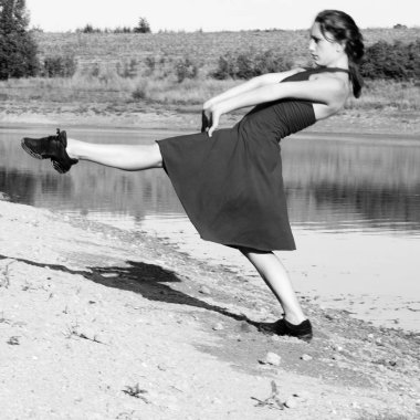 Çağdaş dansçı bir göl yanındaki yeni bir dans doğaçlama. O siyah bir elbise giyiyor. O bir bacak ve kollarını yatay olarak tutuyor.