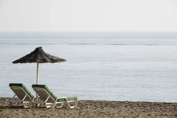 西班牙太阳海岸海滩上的两把椅子和伞 — 图库照片