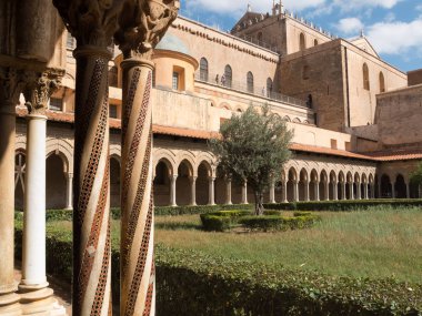 Monreale, Sicilya, İtalya-14 Eylül 2016 : Monreale Arap-Norman Katedrali'nin Benedictine manastırı. Sütunlar altın ve renklerde desen bantları ile dekore edilmiştir. Başkentler, Eski ve Yeni Ahit'ten anlatı döngülerini içerir..