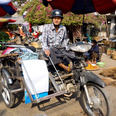 Mandalay, Myanmar - 16 Ocak 2016: Vintage siyah kask takan adam eski bir arabanın üzerinde oturuyor.