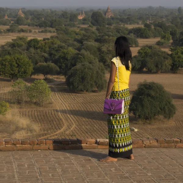 缅甸蒲甘 2016年1月28日 匿名的亚洲妇女正在从其中一座寺庙的顶端看许多寺庙 她穿着黄色的衣服 她站着 — 图库照片
