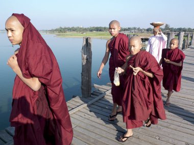 Amanapura, U Bein Köprüsü, Mandalay, Myanmar (Burma) - 15 Ocak 2016 : Taungthaman gölü nün üzerindeki tikağacı U Bein masasından geçerken derin kırmızı cüppegiymiş genç Budist rahipler.