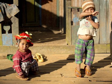 Mindat, Chin State, Myanmar (Burma) - 2 Şubat 2016 : Evlerinin önündeki steet'te oynayan iki birmanyalı çocuk. Çek pantolon giyiyorlar. Birinin kırmızı şapkası çiçekli, diğerinin yün şapkası var..