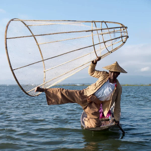 缅甸掸邦因勒湖 2016年1月26日 单腿划船的渔民用一只手和一只脚拿着传统的圆锥网 他站在竹船的前面 他戴着一顶大亚洲帽子 — 图库照片
