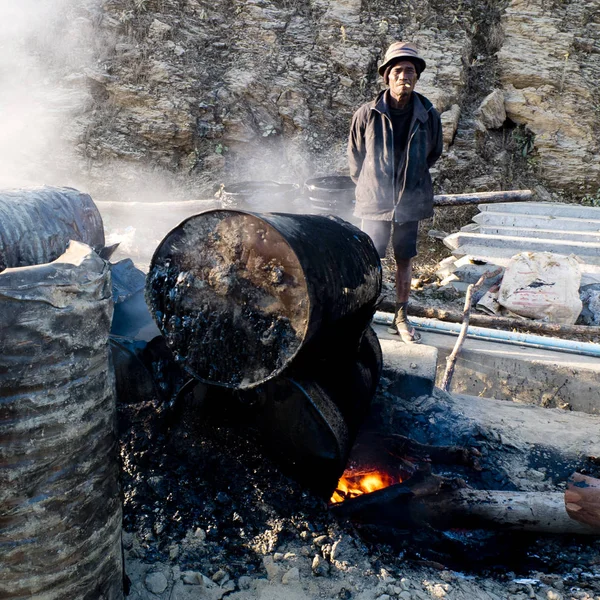 Mindat, Chin State, Myanmar (Burma) - 31 Ocak 2016 : Katran ın hazırlanmasını izleyen işçi , köyün bir sokağında büyük davullar içinde