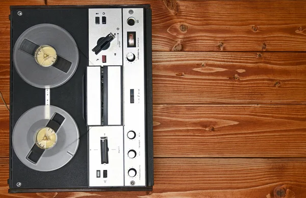 Vintage reel to reel tape recorder on a wooden background.Retro
