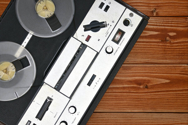 Vintage reel to reel tape recorder on a brown wooden background. Retro tape recorder from the Soviet Union