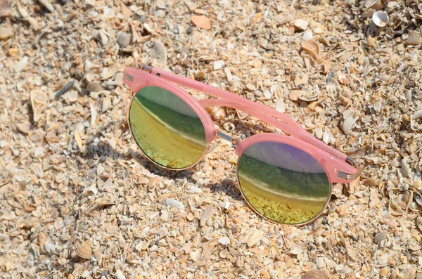 Růžové sluneční brýle proti slunci na plážovém písku — Stock fotografie