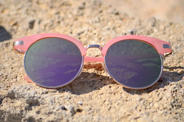 Occhiali da sole rosa contro il sole sulla sabbia della spiaggia — Foto Stock