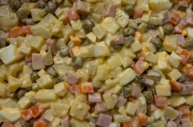 Bir Rus (Fransız) salatası ev yapımı mayonez ve bezelye, sarı peyniri, haşlanmış yumurta, jambon, havuç, patates, salatalık turşusu ile yakın çekim