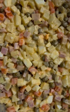 Bir Rus (Fransız) salatası ev yapımı mayonez ve bezelye, sarı peyniri, haşlanmış yumurta, jambon, havuç, patates, salatalık turşusu ile yakın çekim