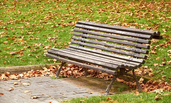 Panchina marrone foglie autunnali in città — Foto Stock