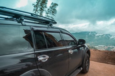 Doğada büyük siyah bir araba park ediyor.