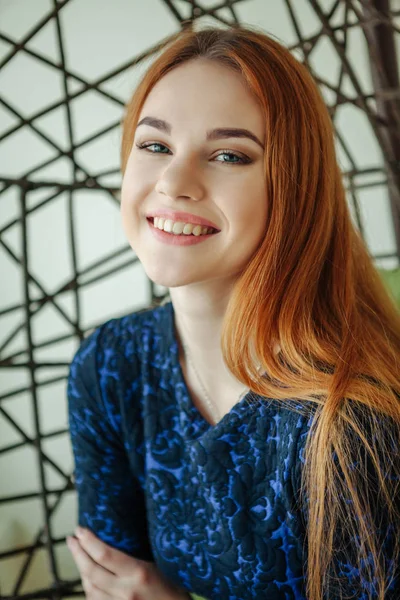 Schöne junge Frau sitzt in einem Hängesessel im Zimmer — Stockfoto