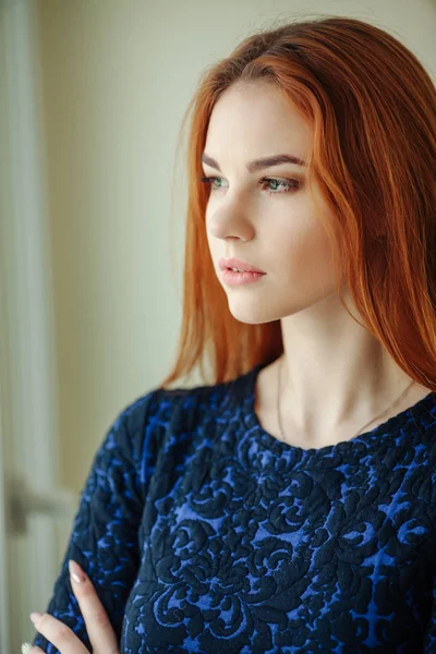 Pencerenin yakınındaki Kızıl saçlı güzel bir genç kadın portresi