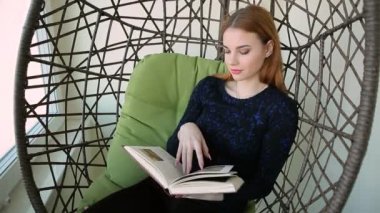 Güzel genç kadın bir fincan sıcak çay veya kahve ile bir kolye sandalyede oturur