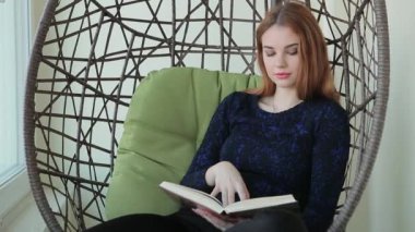 Güzel genç kadın bir fincan sıcak çay veya kahve ile bir kolye sandalyede oturur