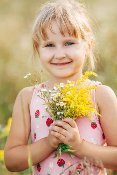 Menina doce em um prado com flores selvagens da primavera — Fotografia de Stock