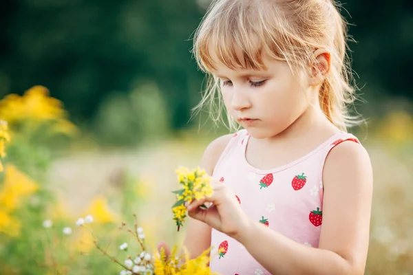 Menina doce em um prado com flores selvagens da primavera — Fotografia de Stock