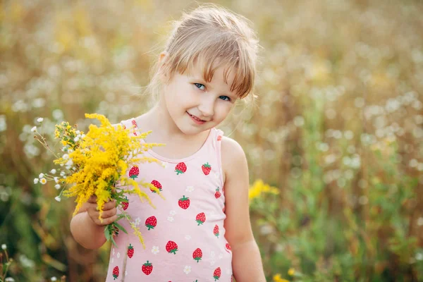 Menina doce em um prado com flores selvagens da primavera — Fotografia de Stock