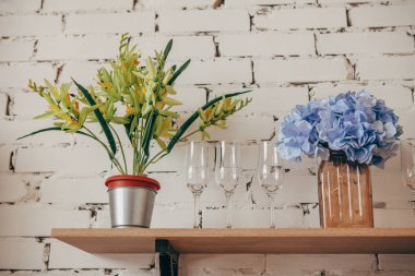 Mutfak içi: saksı, bir vazo çiçek ve bardaklar rafta. Konforlu ev içi