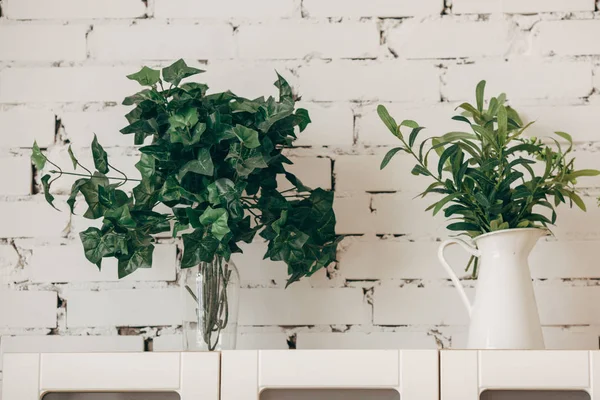 Kitchen interior: flower pot, a vase of flowers and glasses on the shelf. Cozy home interior.