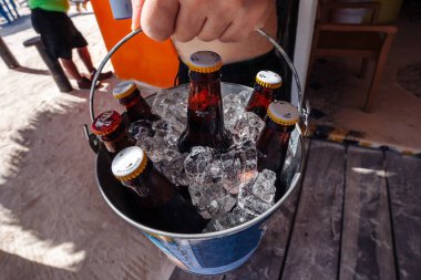 Bir adam sahilde elinde bira ile bir buz kovası Close-Up