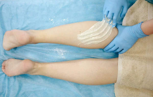 Depilacja woskiem w salonie spa. Kosmetyczka nakłada wosk na damskie nogi. Szczelnie-do góry. — Zdjęcie stockowe