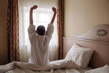 Genç kadın bornoz uygun uyandırma ve Oda onun kollarında dışarı uzanan. Seyahat ve tatil kavramı