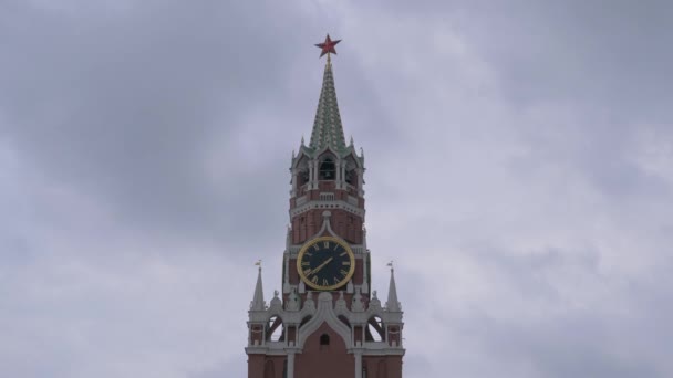 Reloj en la Torre Spasskaya en la Plaza Roja bajo un cielo sombrío en un día gris nublado — Vídeo de stock