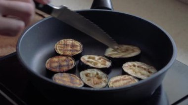 Patlıcanlar tavada kızartılır. Dişi el patlıcan parçaları karıştırır. Close.