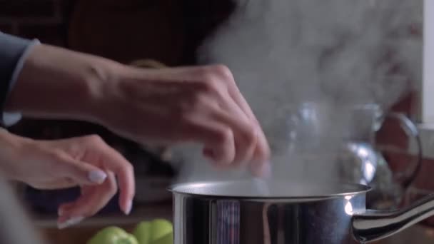 La pentola è sul fornello in cucina. La mano femminile mescola il porridge. Acqua bollente sale vapore . — Video Stock