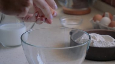 Dişi eller şeffaf bir kaseye bir yumurta kırmak.