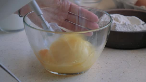 Las manos de las mujeres mezclan los huevos de la batidora en un bol . — Vídeo de stock