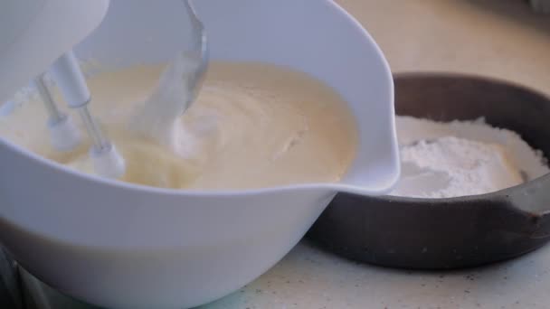 Womens hands mix the mixer eggs in a bowl. Add flour to the bowl. — Stock Video