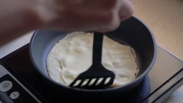 Las manos giran el panqueque en la sartén mientras se cocinan los panqueques . — Vídeo de stock