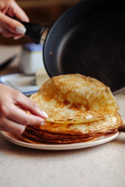 Sıcak klasik Rus ince krep yığını. Rustik tarz. Rus gözleme haftası için geleneksel - Maslenitsa. Dişi el tavadan krep koyar.