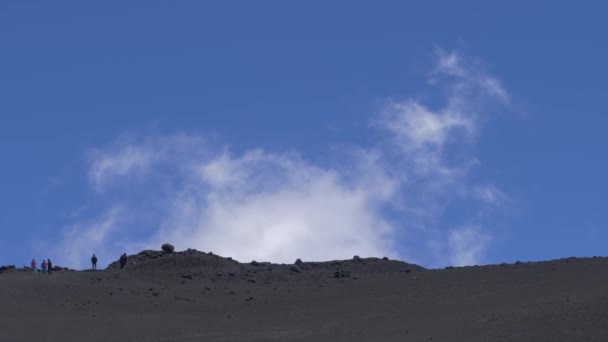 Люди ходят по окаменелой лаве на вулкане Этна. Белое облако над поверхностью вулкана. Сицилия, Италия — стоковое видео