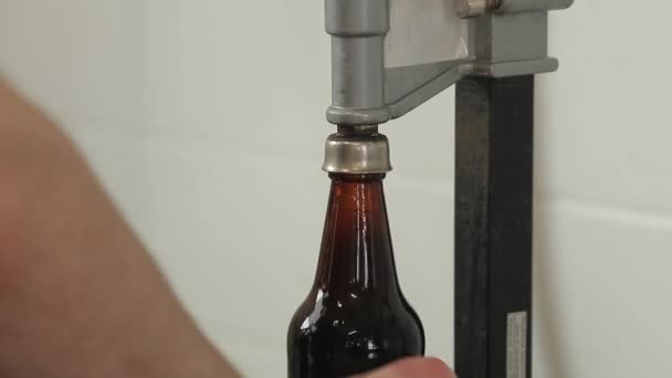 Détail d'un outil pour fermer ou embouteiller des bouteilles de bière. Homme fermant une bouteille de bière avec un bouchon . — Video