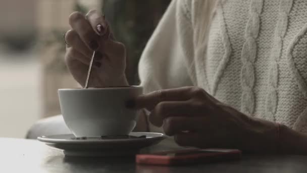 Девушка пьет кофе и смотрит в телефон — стоковое видео