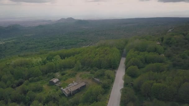 Aerial view of the slope of Mount Etna. Flying drone over the road overlooking the foot of the mountains and the coast of Sicily. Italy. — Stock Video