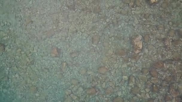 Aerial view of the sea coast. Stones are visible through the clear water at the bottom. — Stock Video