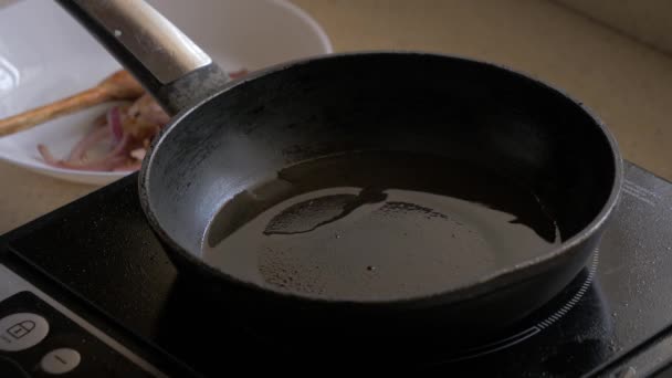 Женская рука наливает масло в сковородку и кладет нарезанные шампанское в сковороду . — стоковое видео