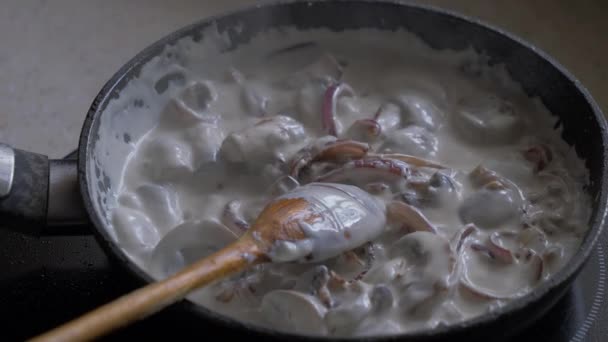 I funghi con crema e cipolle sono fritti in una pentola . — Video Stock