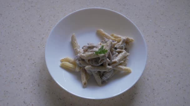 Een vrouwelijke hand decoreert pasta met kaas en champignons met peterselie takjes. Uitzicht vanaf boven. — Stockvideo